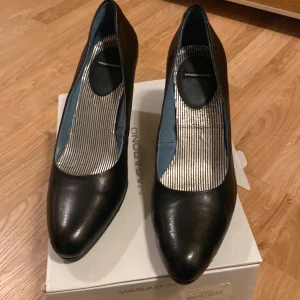 Svarta pumps från Vagabond - Snygga svarta pumps från Vagabond i skinn. De har en elegant spetsig tå och en stabil klack som ger bra stöd. Perfekta för både vardag och fest! Skorna är i mycket bra skick och kommer i originalkartong.