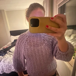 Lila stickad tröja - Säljer en superfin lila stickad tröja med ett luftigt mönster. Den är perfekt för höst, vinter och vår, och har en mysig, loose passform. Tröjan har långa ärmar och en ribbad kant vid halsen. Perfekt för att hålla sig varm och stilren!