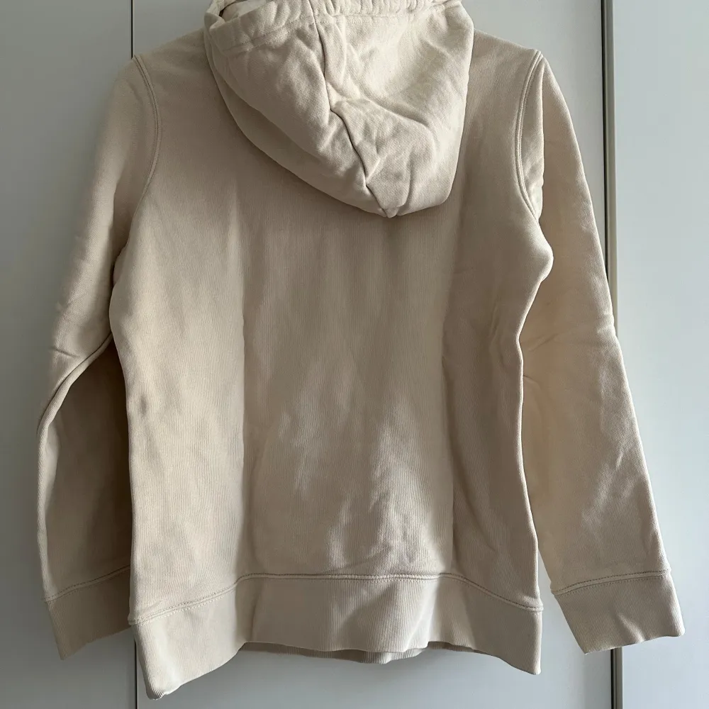 Säljer en snygg beige hoodie från Adidas med det klassiska trefoil-loggan i vitt på framsidan. Den har en skön passform med långa ärmar och en praktisk huva med dragsko samt fickor framtill. Perfekt för både vardag och chill! 🧢. Hoodies.