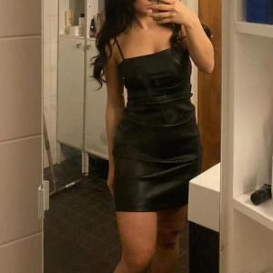 Kort Skinnklänning  - Kort skinnklänning med spaghetti straps. Mini festklänning. Veckad.