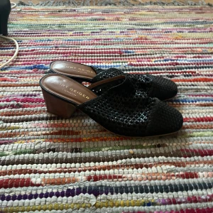 Svarta klackskor från Kurt Geiger - Snygga svarta klackskor från Kurt Geiger i flätat material. Perfekta för både vardag och fest med en bekväm klackhöjd. Skorna har en elegant design och är i mycket bra skick. Passar perfekt till sommarens alla tillfällen!