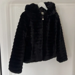 Svart fakepäls jacka med huva - Svart pälsjacka (ej äkta päls) med luva , använd fåtal gånger. 
