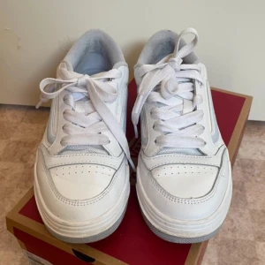 Vita sneakers från Vans - Säljer ett par vita Vans sneakers i bra skick. De har en klassisk design med snörning och en bekväm passform. Perfekta för vardagsbruk och passar till det mesta. Sulan har det ikoniska Vans-mönstret för bra grepp.