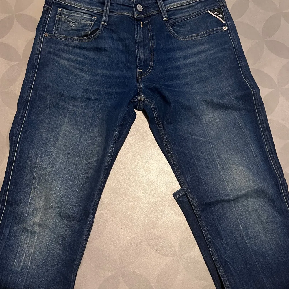 Säljer ett par snygga blå jeans från Replay i modellen Anbass. De har en klassisk femficksdesign med dragkedja och knapp. Jeansen är i mycket bra skick och har en skön passform som är normal. Perfekta för både vardag och fest!. Jeans & Byxor.