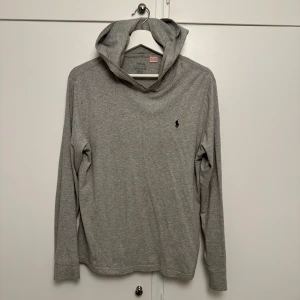 Grå långärmad hoodie från Ralph Lauren - Säljer en stilren och bekväm grå hoodie från Ralph Lauren. Den är i mycket bra skick och har en klassisk design med en liten broderad logga på bröstet. Perfekt för både höst och vår, och passar till de flesta tillfällen. Skön och enkel att matcha med andra plagg! XL i barn storlek (18-20 år)