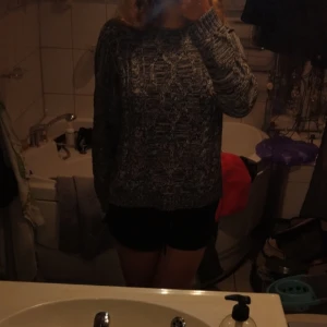 Mönstrad stickad tröja - Säljer en mysig stickad tröja i mörkgrått med ett unikt mönster. Perfekt för kyliga dagar och passar bra till både jeans och kjol. Tröjan har långa ärmar och en bekväm passform. Perfekt för höst och vinter!