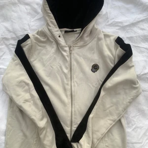 Beige hoodie från Vichy - DEN LEGIT SJÖNASTE ZIP UPPEN JAG ANVÄNT I HELA MITT LIV, måste dock sälja den då ja ätit lite för mke på sistone🙃Säljer en snygg beige hoodie från Vichy i bra skick. Den har en dragkedja framtill och en cool svart detalj längs ärmarna. Perfekt för höst och vår, med en mysig huva för extra värme. Passar både till vardags och chill dagar. Nypris: 2🐟