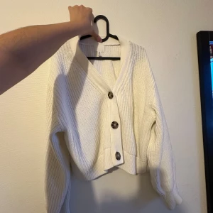 Vit stickad kofta med knappar - Mysig vit stickad kofta i damstorlek M. Den har stora knappar framtill och en skön, ribbad struktur. Perfekt för kyliga höst- och vinterdagar. Passar både till vardags och lite finare tillfällen. 🧶✨