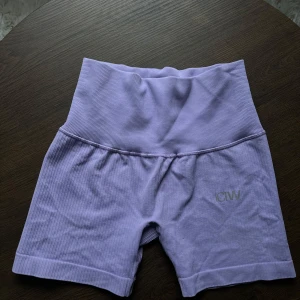Lila ribbade träningsshorts från ICANIWILL - Säljer ett par snygga lila ribbade träningsshorts från ICANIWILL. De är högmidjade och perfekta för gymmet eller yoga. Materialet är stretchigt och bekvämt, vilket ger en bra passform. Shortsen är i mycket bra skick och redo för nya äventyr!💜
