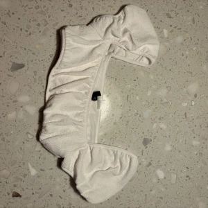 Vit offshoulder topp från H&M - Säljer en söt vit offshoulder topp från H&M Divided. Den har en volangdetalj som ger en romantisk touch och är perfekt för sommardagar. Toppen är i bra skick och passar till både vardag och fest. Perfekt att matcha med ett par jeans eller en kjol!