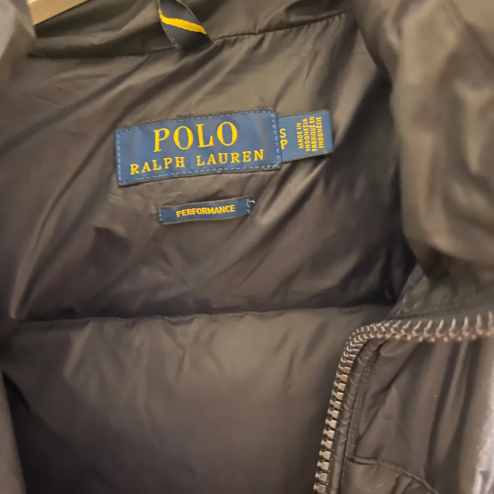 Säljer en snygg svart dunjacka från Polo Ralph Lauren i storlek S. Jackan har en dragkedja framtill och en liten röd logga på bröstet. Perfekt för kalla vinterdagar med sin varma och quiltade design. Den har också en praktisk huva för extra skydd mot väder och vind. Nästan aldrig använd. Nypris ca 4500. Jackor.