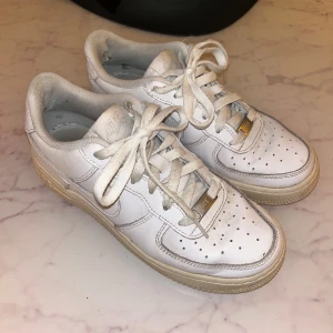 Vita Nike Air Force 1 sneakers - Säljer ett par klassiska vita Nike Air Force 1 sneakers i bra skick. Sulan är något sliten men fortfarande bekväm och inget som syns på utsidan! Dom är köpta för cirka 1200kr.