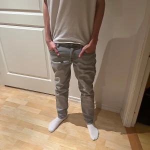 Jack and Jones  - Säljer ett par grå jeansbyxor i bra skick. De har en normal passform och är perfekta för både vardag och fest. Byxorna har en klassisk design med fem fickor och en knappgylf. Perfekta för höst och vår!