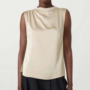 Beige ärmlös topp - Topp ifrån Vila. Nypris: 400kr. Snygg och stilren beige ärmlös topp i satin. Perfekt för både vardag och fest. Använt 1 eller 2 gånger.
