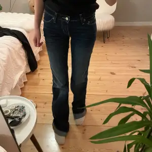 Säljer ett par snygga mörkblå jeans i bra skick. De har en klassisk femficksdesign och är lågmidjade med en bootcut-stil. Perfekta för både vardag och fest! Passar bra till en t-shirt eller en snygg blus.