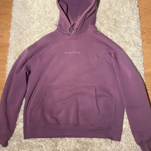 Lila hoodie junkyard - district fortysix - Säljer en snygg lila hoodie med ett coolt sol- och månmotiv på ryggen. Den har lite fläckar på sig. Den har en stor ficka fram och en bekväm huva. Perfekt för mysiga dagar eller som ett statement-plagg. Passar både till vardags och chillkvällar. 💜