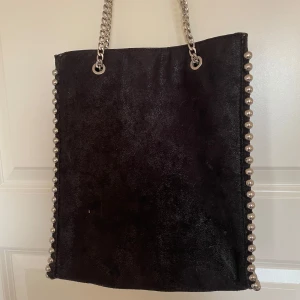 Svart väska - Snygg svart lite glittig axelväska med coola kedjedetaljer längs kanterna från Zara. Väskan har en stilren design och är perfekt för både vardag och fest. Insidan är rymlig med flera fack för organiserinh. Skriv för fler bilder eller om ni har frågor!💓