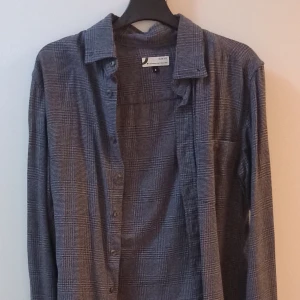 Grå rutig skjorta - Säljer en stilren grå rutig skjorta med långa ärmar. Perfekt för både vardag och fest. Skjortan har en klassisk krage och knappar framtill. Den är i bra skick och passar perfekt till höst- och vårsäsongen. Ett måste i garderoben för en tidlös look!