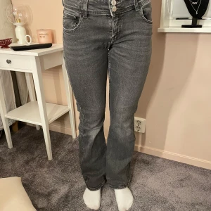 Grå jeans med bootcut - Säljer ett par snygga grå jeans i bootcut-stil. De är lågmidjade med knappar fram och har en klassisk femficksdesign. Perfekta för både vardag och fest! 🖤 Från Gina tricot! Sparsamt använda!