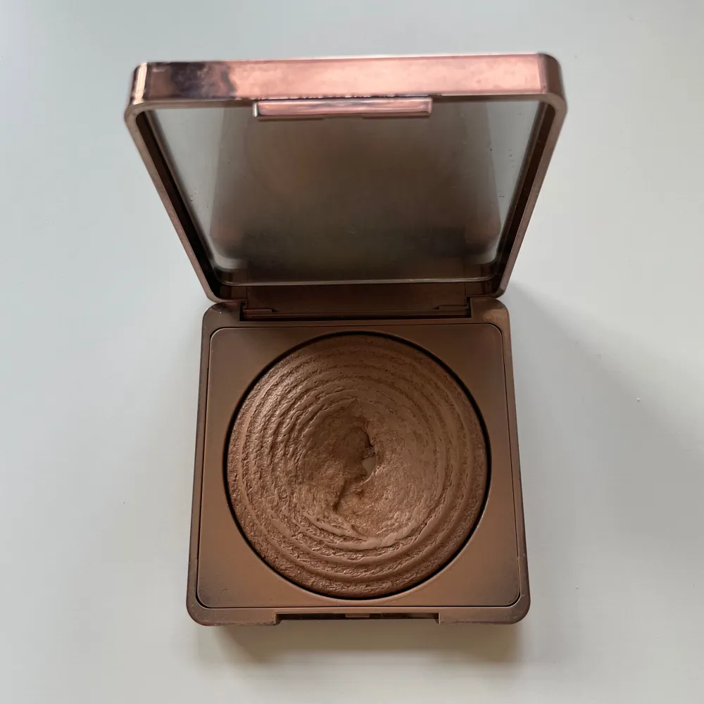 Snygg bronzer i en stilren, fyrkantig förpackning med roséguldfärgad finish. Perfekt för att ge ansiktet en solkysst look med en subtil glöd. Den har en vacker, vågig textur som gör appliceringen jämn och enkel.. Skönhet.