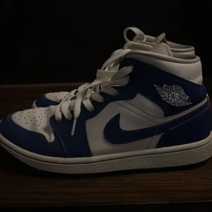 Nike Air Jordans i blått och vitt - Säljer ett par Nike Air Jordans i snygg blå och vit färgkombination. Skorna har klassisk snörning och är i bra skick. Perfekta för både vardag och festliga tillfällen. Storlek herr 42. Passa på att köpa dessa ikoniska sneakers! Lite creesade