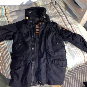 Svart jacka från Parajumpers - Säljer en svart Parajumpers jacka i mycket bra skick. Den är quiltad och har en mysig pälsfodrad insida. Jackan har flera praktiska fickor och en dragkedja framtill. Perfekt för kalla höst- och vinterdagar. Passar både till vardags och mer äventyrliga aktiviteter. 🖤 helt nyt kostar 9 123 kr men jag säljer den för  6000