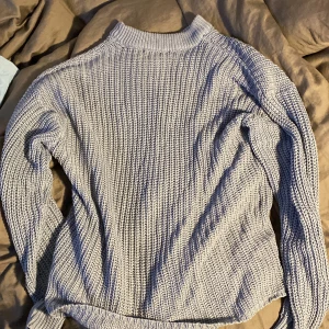 Grå stickad tröja från 157 - Säljer en blå stickad tröja från 157 i storlek M. Tröjan har en mysig och varm känsla, perfekt för höst och vinter. Den har långa ärmar och en liten skada på magen som syns på bild. Passar bra till vardags eller en avslappnad dag hemma.