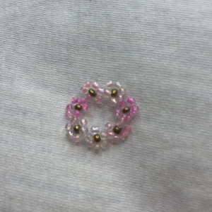  blommig ring - Säljer  en söt ring med blommor i rosa och vita nyanser. ringen ger en fin touch med sina små blommor. Perfekt för att liva upp vilken outfit som helst! 🌸✨