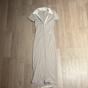 Beige ribbad klänning - Säljer en superfin beige ribbad klänning med krage och korta ärmar. Den har en v-ringad design och är i ett mjukt och stretchigt material. Perfekt för både vardag och fest! 🥰