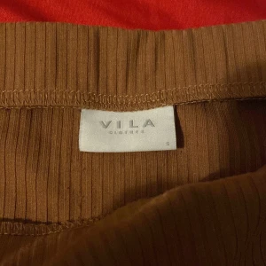 Brun ribbad kjol från Vila - Säljer en snygg brun ribbad kjol från Vila i storlek S. Kjolen är i ett mjukt och stretchigt material som ger en bekväm passform. Perfekt för både vardag och festliga tillfällen. Den har en elastisk midja för extra komfort. Passar bra till höst- och våroutfits! Jag har aldrig använt den själv, men den är lite ostrykt, det är inget jag inte kan fixa🤗