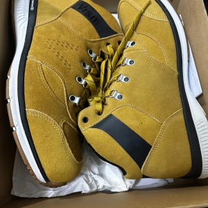 Helt nya oanvända. Kostar 3000kr - Säljer ett par snygga gula mocka boots från Vision i storlek herr 46. De har en cool svart detalj på sidan och robust snörning. Perfekta för höst och vår med sin slitstarka sula och bekväma passform. Helt nya i kartong!