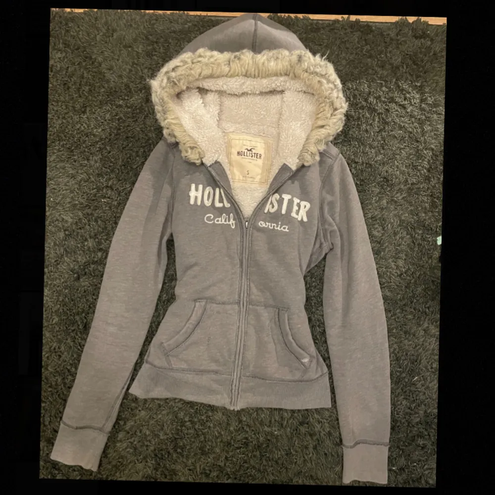 Hoodien har haft hål i fickan som jag har lagat med en ladderstich. Kontakta för flera närbilder på de ihopsydda hålen. Grå zip up hoodie från Hollister med päls/ fur. Jag vet inte riktigt vad den är värd så priset är nog ganska förhandlingsbart. Om ni skriver till mig privat så kan jag också skicka bild påbhur den passar på mig. Den passar bra på mig och jag är xxs, tror den skulle funka för xxxs-s. Kan också mötas upp i istället för att skicka, bor i stockholm.. Hoodies.