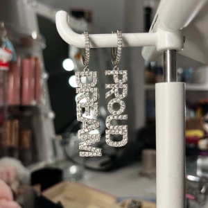 Glittriga örhängen med text från Ioaku - Snygga örhängen från Ioaku med texten 'DREAM' och 'PROUD'. Köpta för 599kr och säljer för 399kr😊. Andvända 4-5 gånger. Skulle kunna mötas upp💕