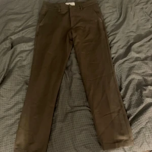 Bruna byxor från Les Deux - Snygga bruna byxor från Les Deux i regular fit. Byxorna har en stilren design med diskreta fickor och en elegant broderad detalj. Perfekta för en stilren look. Passar någon som är 170-180 cm lång