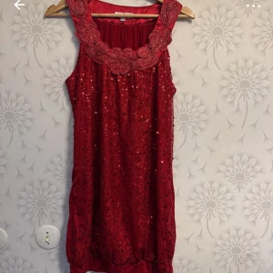 Röd glittrig ärmlös klänning - Snygg röd klänning med glittriga paljetter och ärmlös design. Perfekt för festliga tillfällen med en elegant touch.
