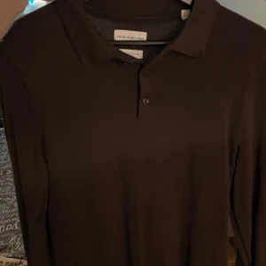 Brun pikétröja från These Glory Days - Snygg brun pikétröja från These Glory Days med långa ärmar och klassisk krage. Perfekt för en stilren look. Har endast använt den 1 gång då tröja var för liten. Så den är i helt nyskick. Ordinarie pris 599, ja säljer den för 399