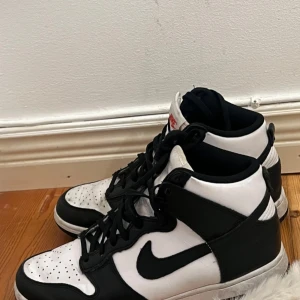Nike Air Jordans i svart och vitt - Snygga Nike Air Jordans i klassisk svart och vit färgkombination. Skorna har en hög modell med snörning och den ikoniska Nike-loggan på sidan. Perfekta för en stilren look. Lite smutsiga men det kan jag tvätta bort.
