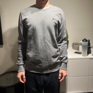Grå sweatshirt från J.Lindeberg - Säljer en stilren grå sweatshirt från J.Lindeberg. Tröjan har långa ärmar och en liten logga på bröstet. Perfekt för en avslappnad look och perfekt nu inför vinter/våren. Vid övriga frågor, tveka inte att höra av dig privat✌️ Storlek M och passar mig super som 189:)