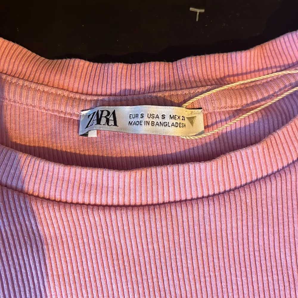 Säljer en söt rosa ribbad topp med volangdetaljer på ärmarna. Perfekt för en somrig look. Toppen är croppad och ärmlös, vilket gör den luftig och bekväm.. Yläosat.