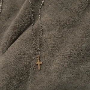 Korshalsband i guld - Elegant halsband med ett litet guldfärgat kors som hänge. Kedjan är tunn och smidig, vilket gör det perfekt för daglig användning eller speciella tillfällen.