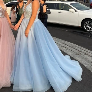 Ljusblå balklänning med paljetter -  ljusblå lång balklänning med glittrig paljettöverdel och djup v-ringning.  perfekt för en bal eller festlig tillställning. Storlek 36-38, använd endast några timmar