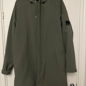 Grön kappa från C.P. Company - Snygg grön kappa från C.P. Company med långa ärmar och stilrena detaljer. Jackan har en knappstängning framtill och praktiska fickor. Perfekt för en stilren look.