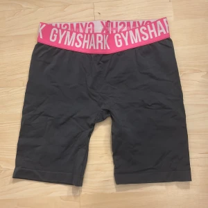 Svarta shorts från Gymshark - Snygga svarta shorts från Gymshark med en bred, elastisk midja i rosa och vit med logotyp. Perfekta för träning och bekväma att bära. Tyvärr är lappen bortklippt men det är storlek S