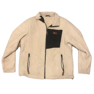 Beige teddyjacka med dragkedja - Mysig beige teddyjacka med svart bröstficka och dragkedja. Jackan har långa ärmar och två framfickor med dragkedja . Perfekt för kyliga dagar. Strl M och knappt använd💞