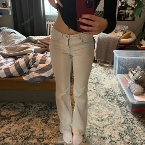 Beige bootcut jeans - Snygga ljusa beige bootcut jeans med låg midja. De går ut från knäna så kan även likna en rak jeansmodell. Klassisk design med fem fickor och knappgylf. Mjukt jeansmaterial och det finns inga slitningar eller skaodor på dem.