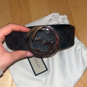Svart bälte från Gucci - Snyggt svart bälte från Gucci med det klassiska GG-mönstret och en stor, rund spänne i silver. 