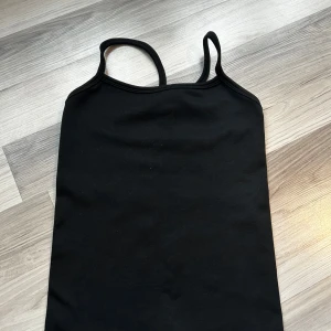 Svart ribbad linnetopp från Stronger - Säljer en svart ribbad linnetopp från Stronger. Toppen har smala axelband och en tight passform, perfekt för en stilren look. Materialet är en blandning av nylon och polyester vilket ger en skön stretch. ⚠️Ni betalar för frakt själva⚠️