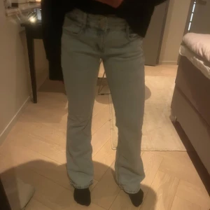 Ljusblå jeans - Säljer ett par ljusblå jeans med bootcut-stil. De har en klassisk design med fem fickor och knappgylf. Perfekta för en avslappnad look.
