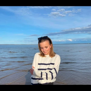 Vit och blå randig tröja - Säljer en snygg vit stickad tröja med blå ränder. Tröjan har långa ärmar och en avslappnad passform. Knappt använd. Tror den är från mango men är osäker.