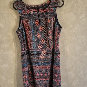 Mönstrad ärmlös klänning från Pretty Girl - Snygg ärmlös klänning från Pretty Girl med ett färgglatt geometriskt mönster i rosa, blått och svart. Perfekt för en somrig look med sin korta längd och bekväma passform.